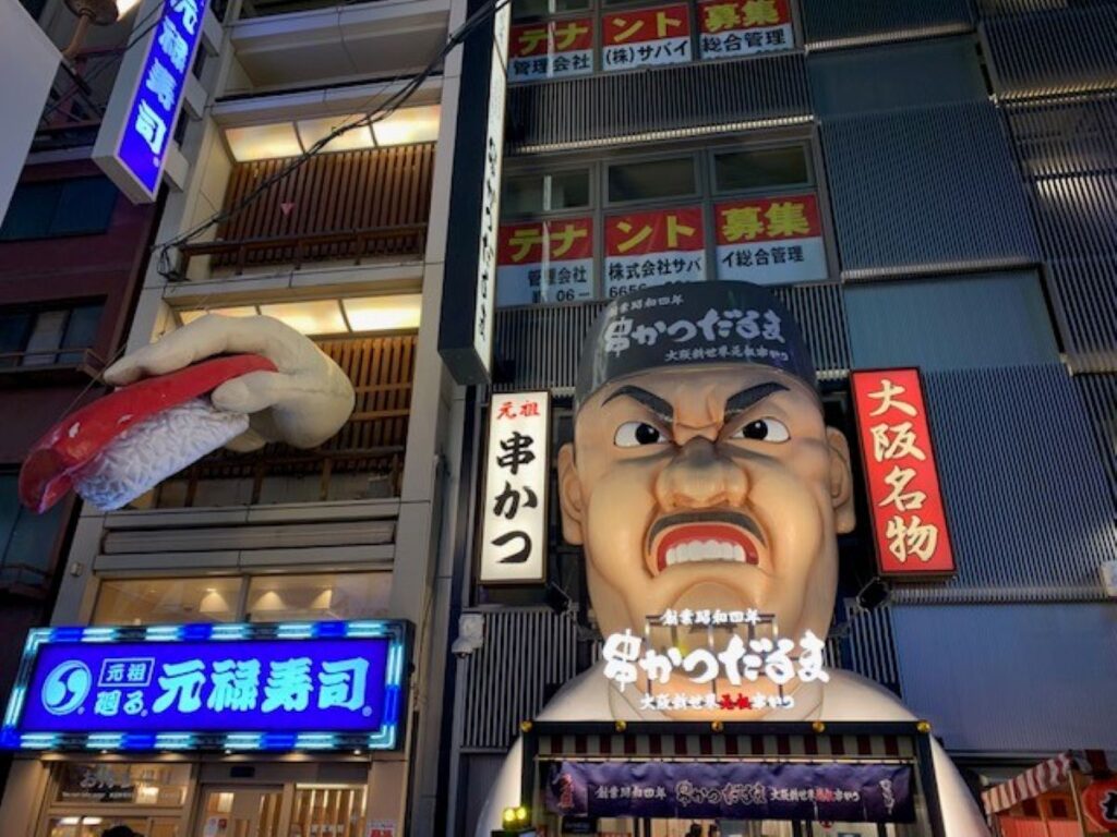 Giant animated chef head and sushi display outside Kushikatsu Daruma restaurant in Osaka's Dotonbori district