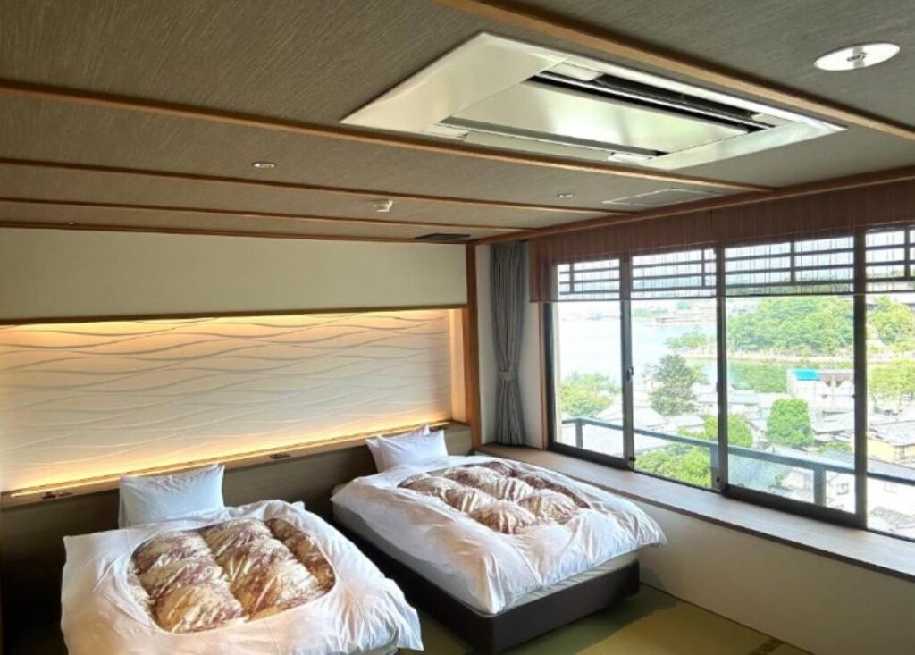 Japanese-style ryokan room with twin futon beds, illuminated headboard, tatami flooring, and garden views