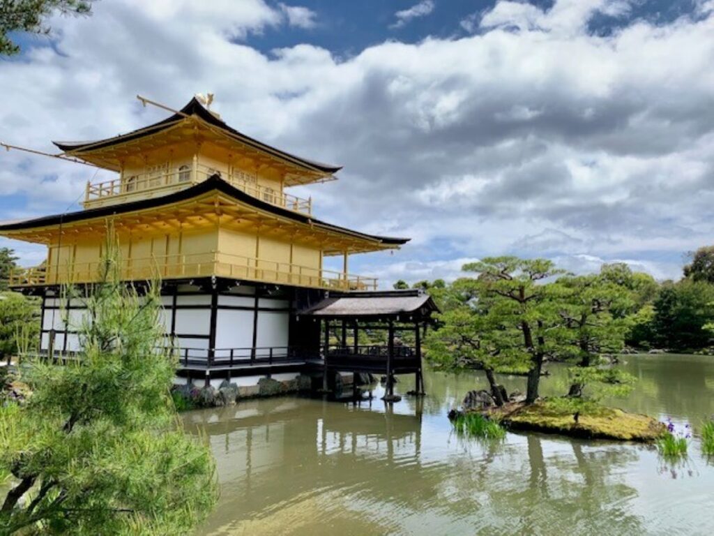 Kinkaku-ji Golden Pavilion temple reflecting in surrounding pond with lush green gardens in Kyoto