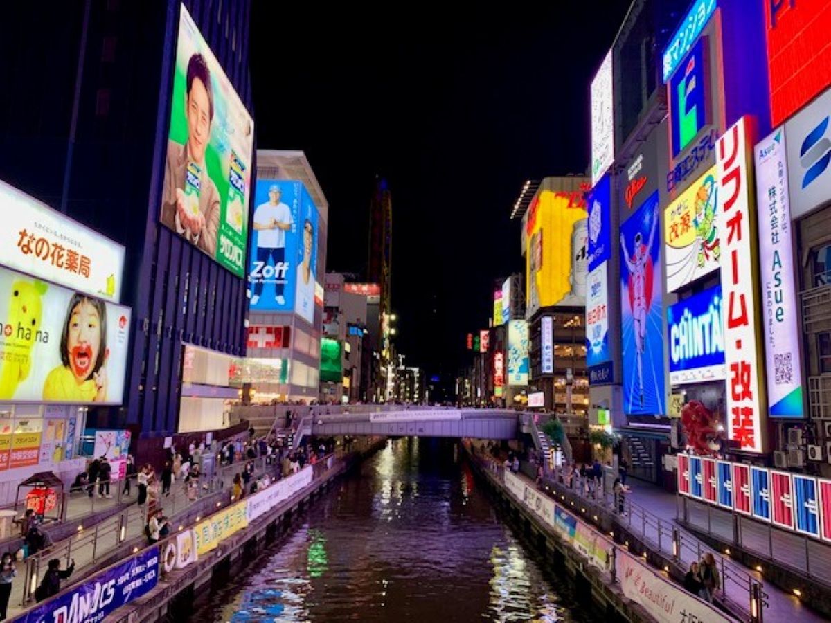 Dotonbori canal at night surrounded by illuminated billboards and neon signs in Osaka's entertainment quarter