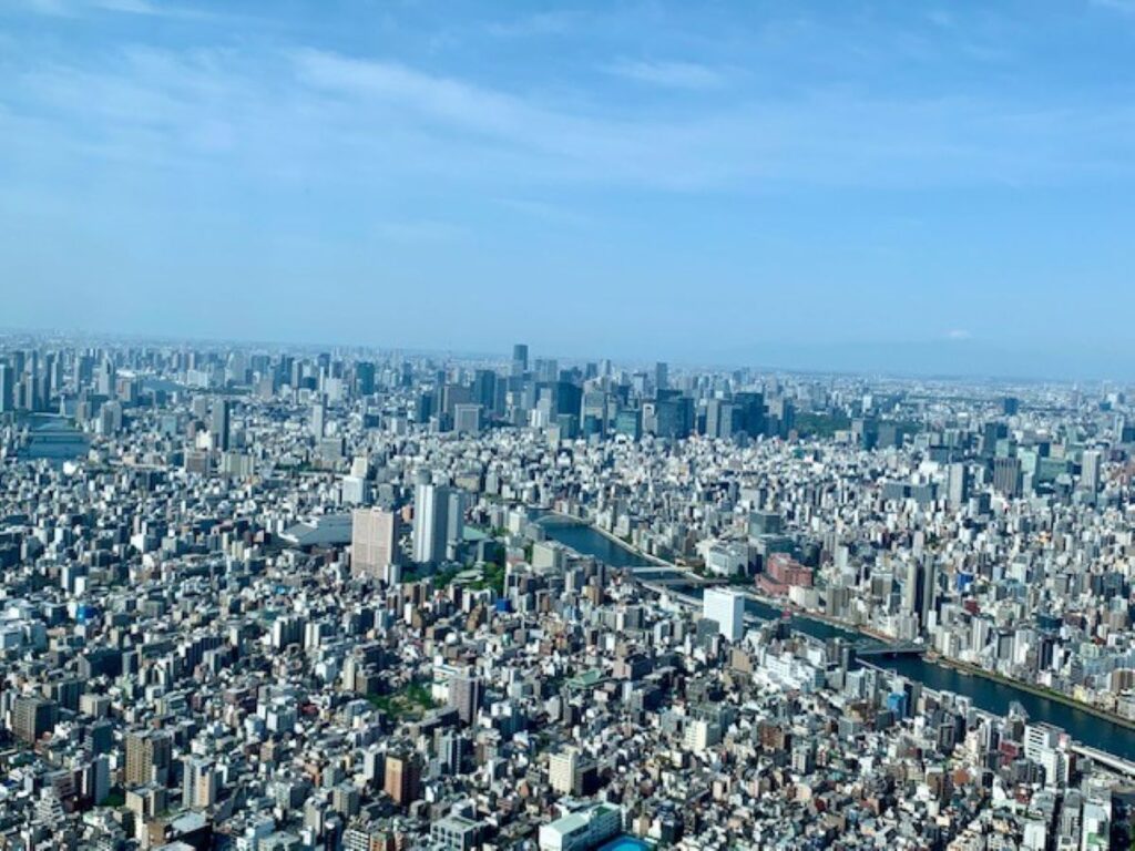 Aerial view of Tokyo's dense urban skyline with Sumida River winding through the city, showcasing Japan's largest metropolitan area