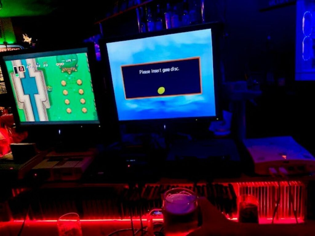 Space Station Retro gaming bar in Osaka with classic consoles and CRT screens, a beer on the counter and neon lighting.