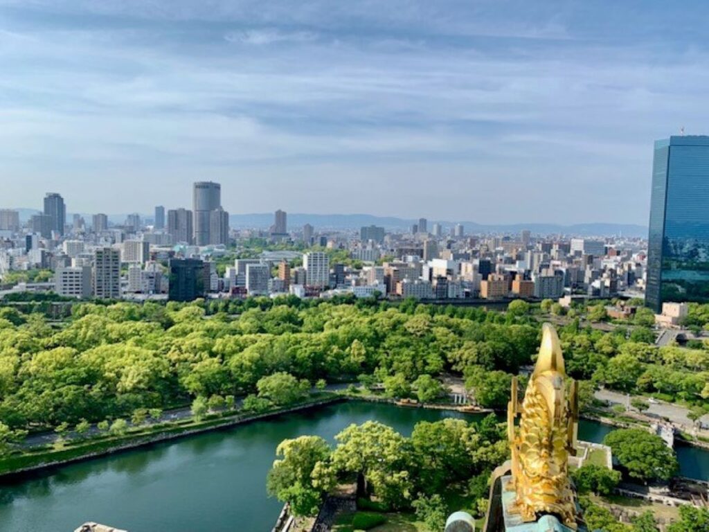 Osaka castle view across Osaka castle park, gold shachihoko with the Osaka city skyline and blue glass tower in the distance