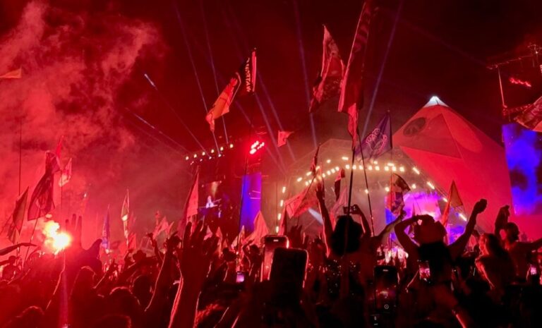 The pyramid stage at Glastonbury Festival. Covered in red light with the crowd waving flags