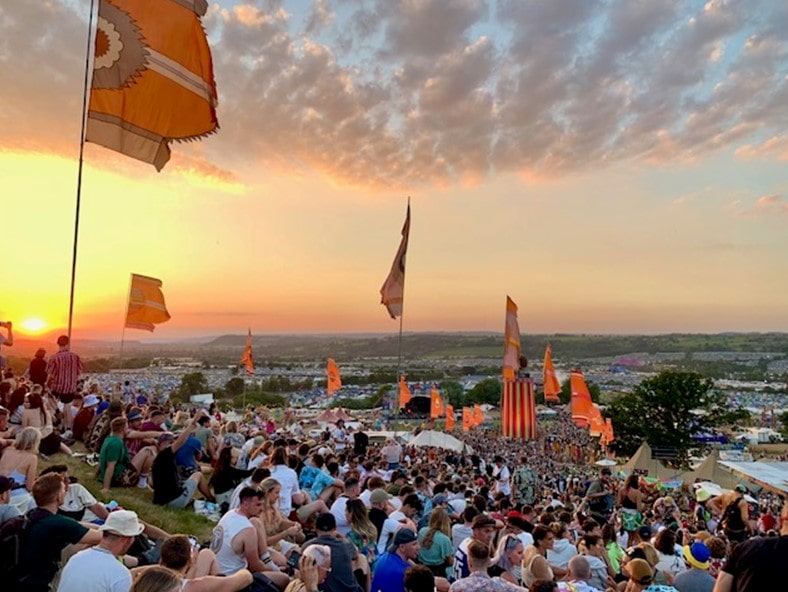 View from the top of the hill at Glastonbury at sunset overlooking a crowd