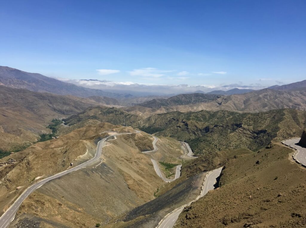 The winding hairpin bends of the Tizi n'Tichka Pass cutting through the rugged High Atlas Mountains in Morocco under a blue sky