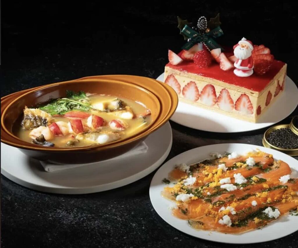 A festive spread with a seafood stew, cured salmon scattered with herbs and egg, and a strawberry cake topped with a Santa figure. (