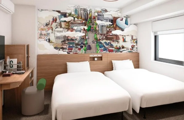 Twin bedroom with white linens, wooden furnishings and distinctive urban mural spanning the wall above headboards. Small desk and window present