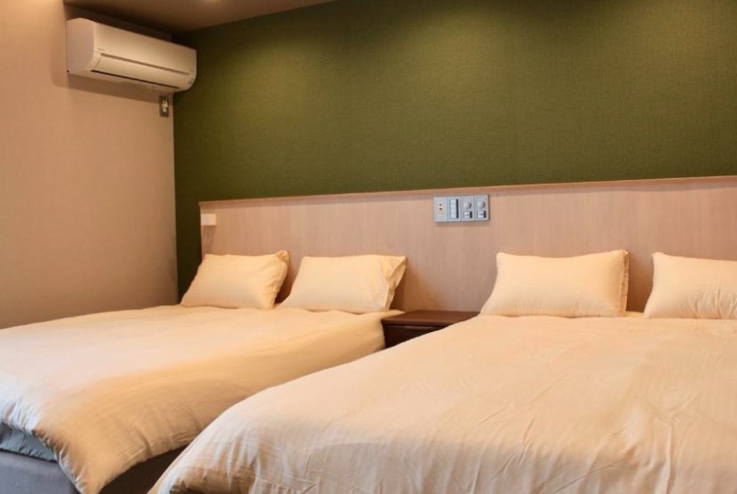 Twin hotel room with green feature wall and matching light wood headboards