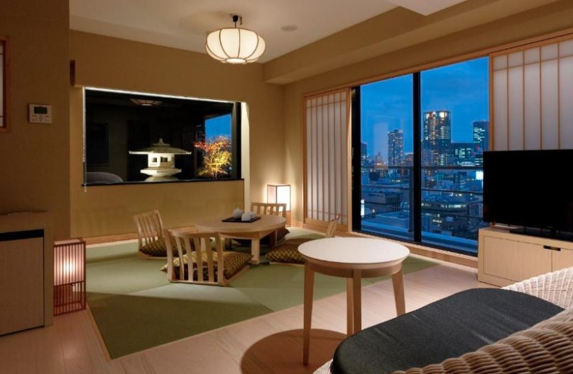 Japanese-style room with tatami flooring, low dining table, and shoji screens. Night-time city views and traditional lantern lighting.