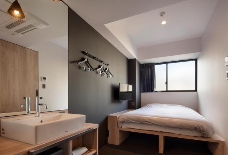 Minimalist room with wooden platform bed, wall-mounted sink and grey accent wall