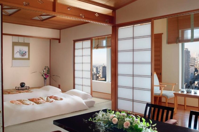 Traditional Japanese-style room with futons, shoji screens and city views, decorated with floral arrangements and wooden details