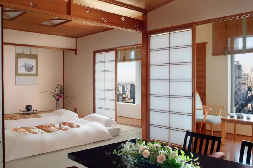 Traditional Japanese-style room with futons, shoji screens and city views, decorated with floral arrangements and wooden details