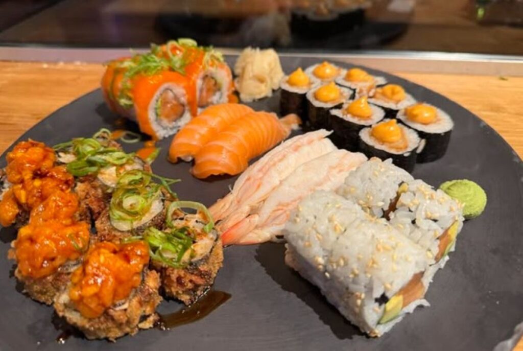 Sushi platter featuring salmon nigiri, California rolls, spicy tuna rolls and assorted maki with wasabi and pickled ginger