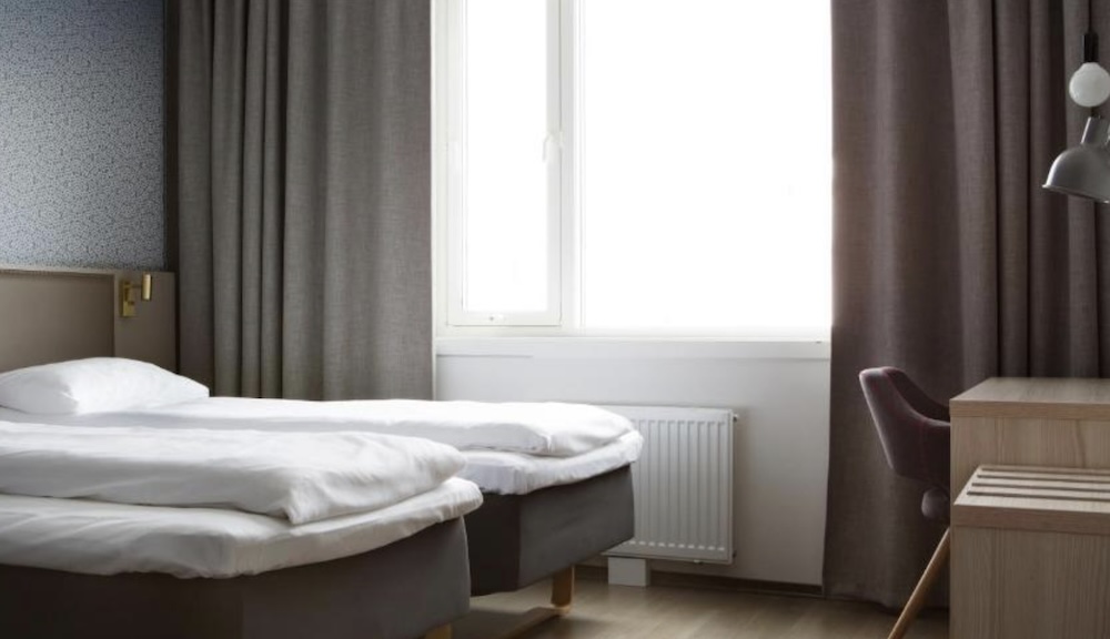 Twin room at the Comfort Hotel Xpress in Tromsø, with two single beds pushed together, a bright window and a small desk with a red chair