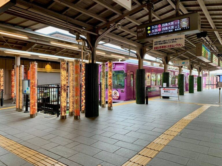 Randen streetcar at traditional Kyoto station platform in Arashiyama with decorative pillars