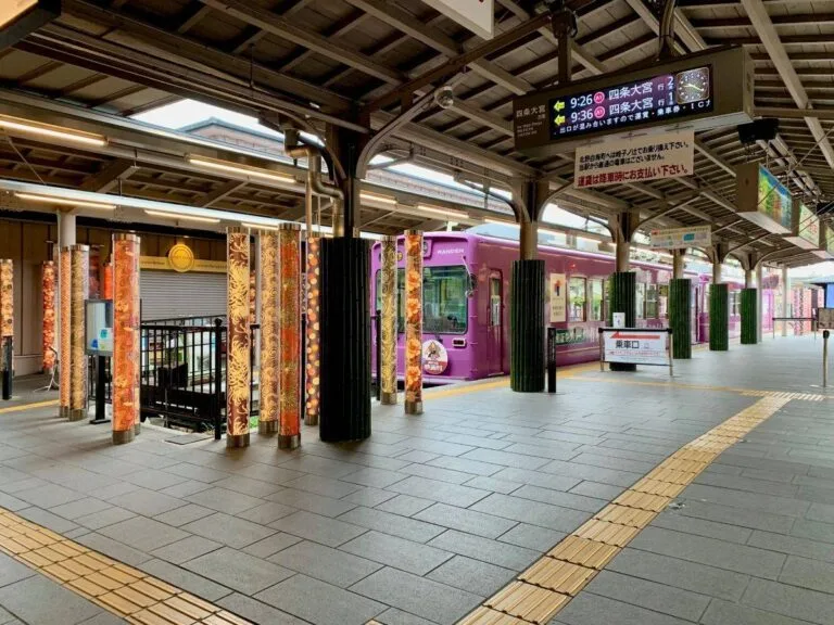 Randen streetcar at traditional Kyoto station platform in Arashiyama with decorative pillars
