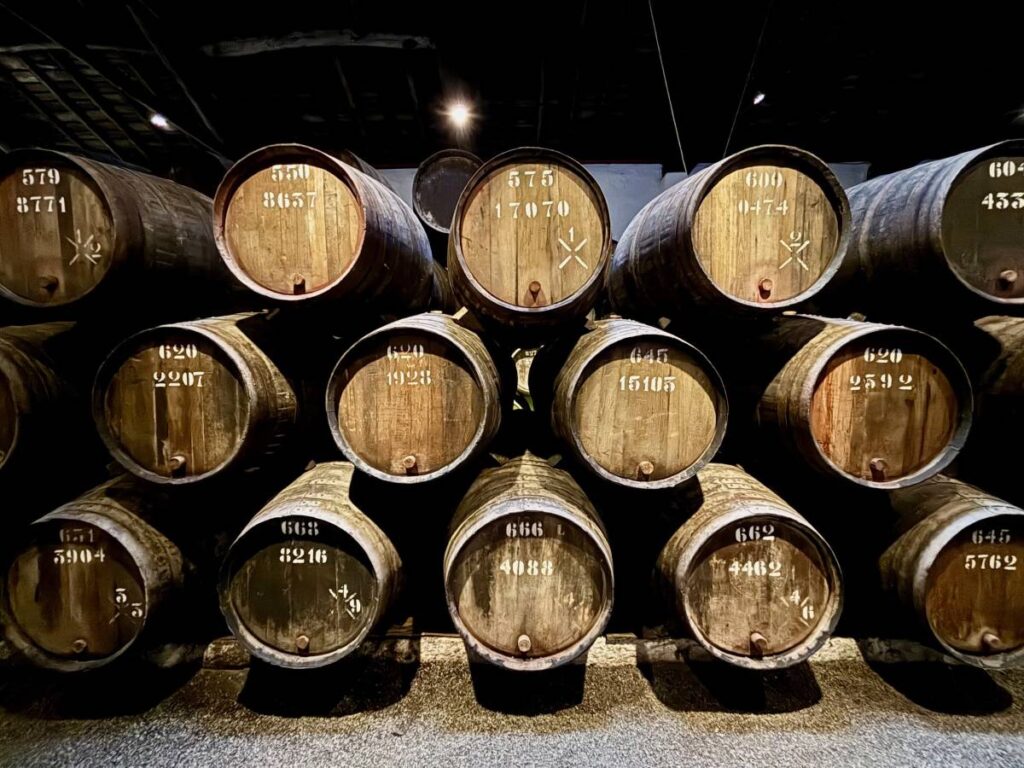 Vintage port wine barrels stacked in traditional cellar, essential for Porto wine tours and tastings during your visit