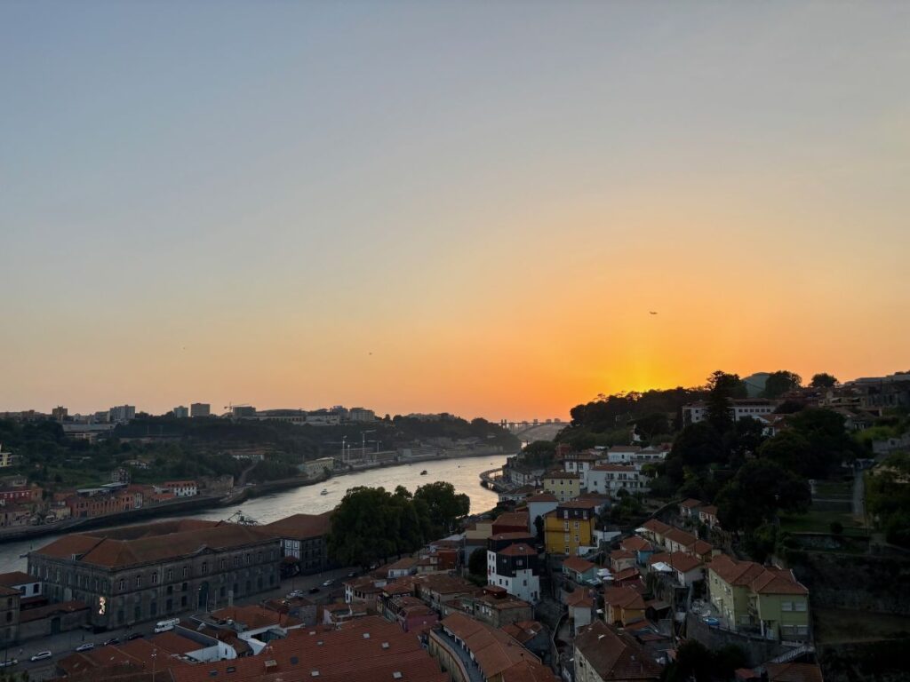 Golden sunset over Douro River and Porto's hillside neighbourhoods, showcasing the city's scenic beauty for travellers