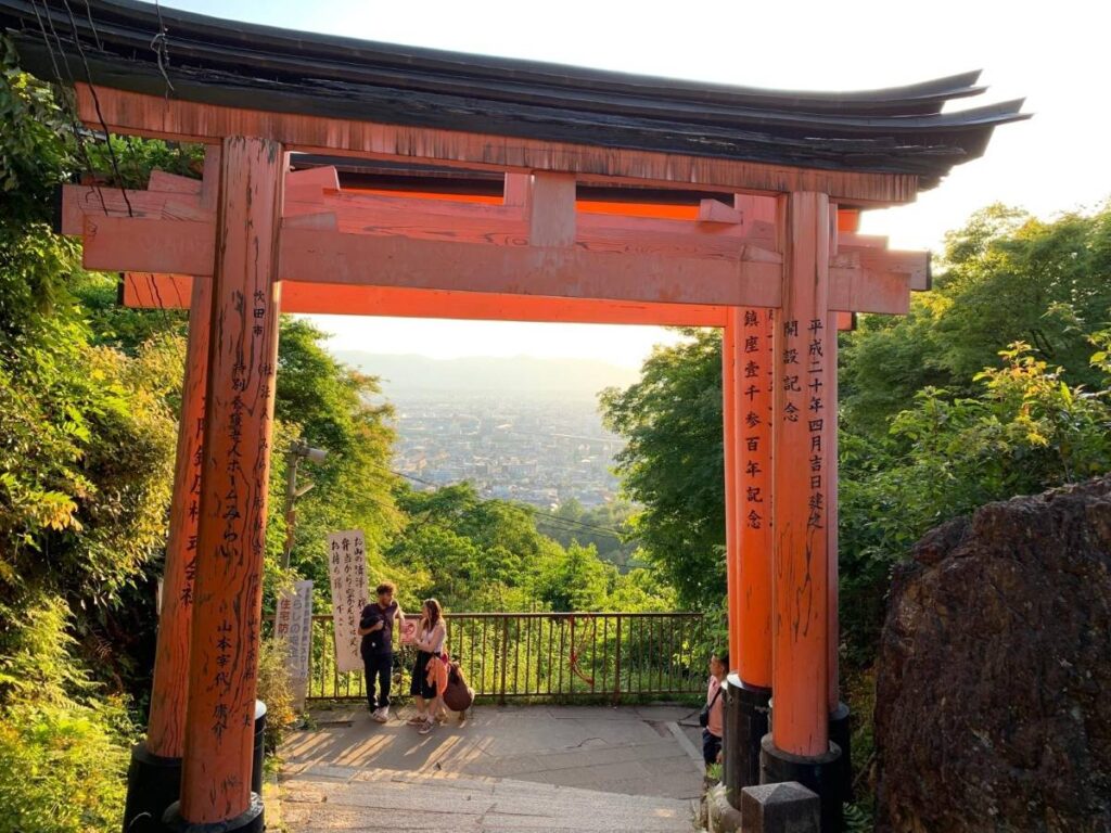 Orange torii gate framing Kyoto city panorama from the top of Fushimi Inari shrine, essential viewpoint for day one sightseeing route
