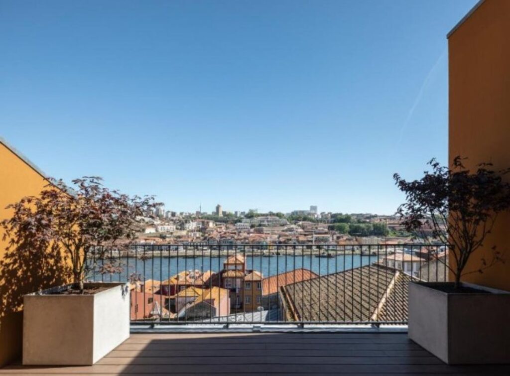 Rooftop terrace overlooking Porto's Douro River with colourful riverside buildings and terracotta rooftops stretching across the city