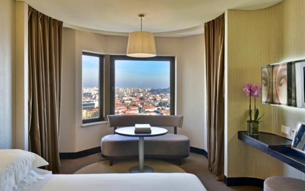 Luxury Porto hotel room with panoramic city views, curved seating nook and contemporary Portuguese design elements