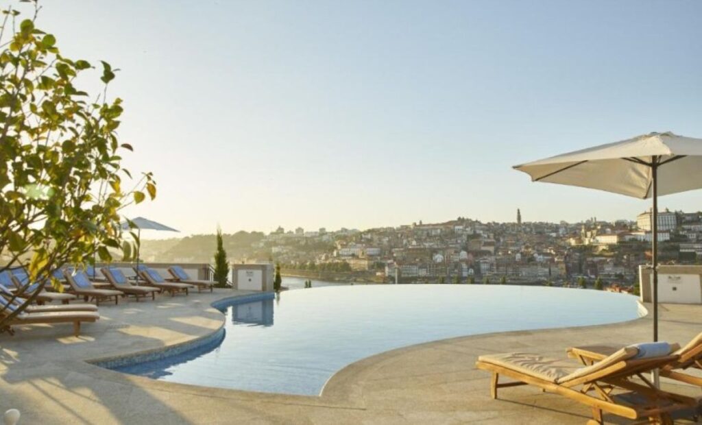 Infinity pool with sun loungers overlooking Porto's hillside cityscape and traditional Portuguese architecture