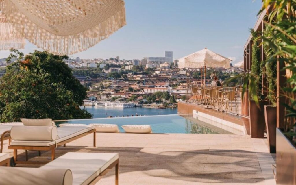 Luxury terrace with infinity pool and wicker parasol overlooking Porto's cityscape and distinctive modern concert hall