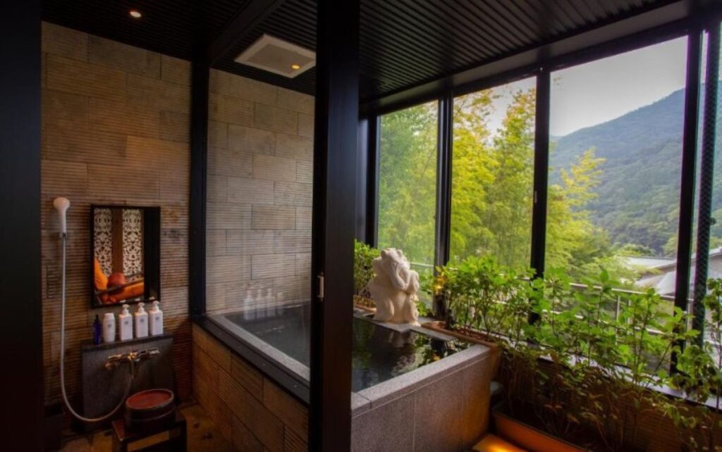 Private stone onsen bath with panoramic windows and indoor greenery at Hakone ryokan