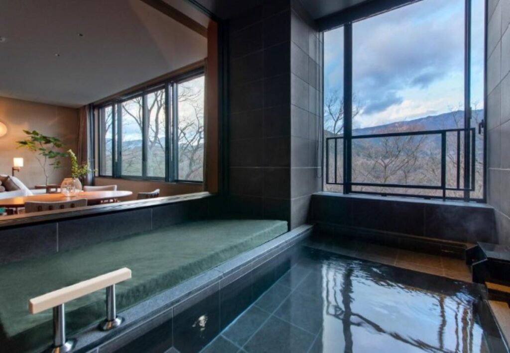 Private in-room onsen with mountain views through large windows at Hakone hot spring resort