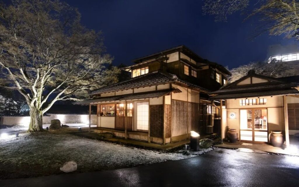 Traditional Japanese ryokan entrance illuminated at night with landscaped garden in Hakone