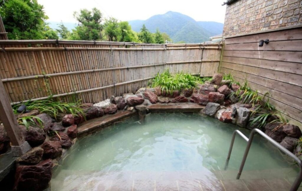 Private outdoor onsen with bamboo fence and mountain views in Hakone