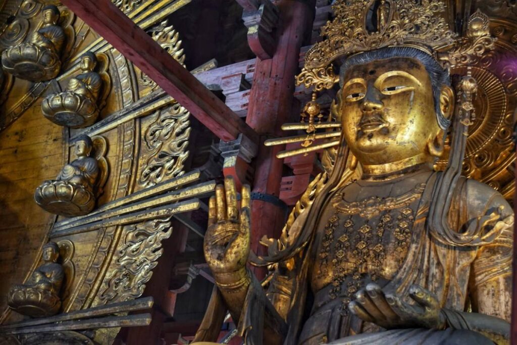 Golden guardian statue with ornate halo holding vajra inside Todai-ji Temple in Nara