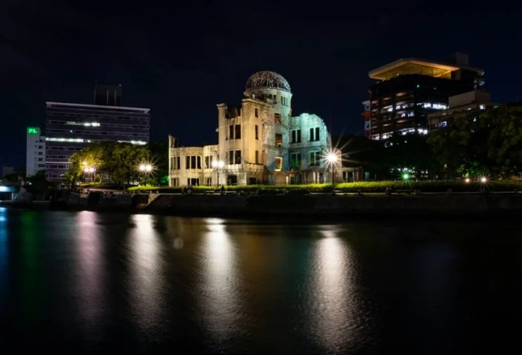 Atomic Bomb Dome illuminated at night beside river in Hiroshima Peace Memorial Park