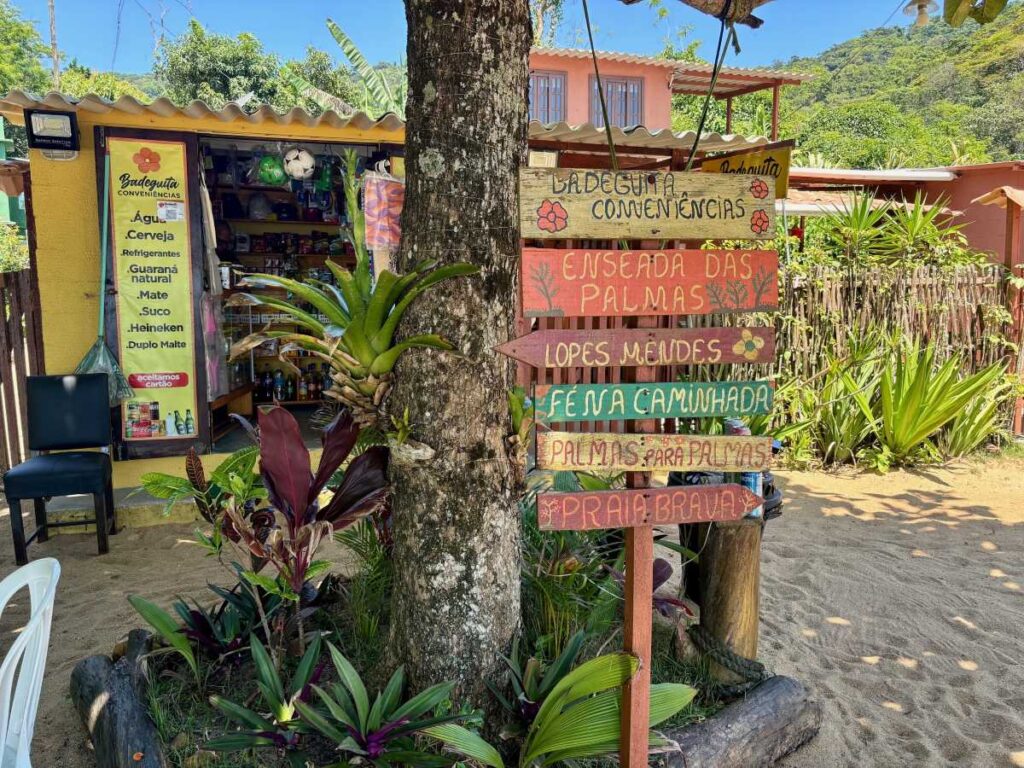 Small convenience shop with hand-painted wooden signs pointing to nearby beaches and trails