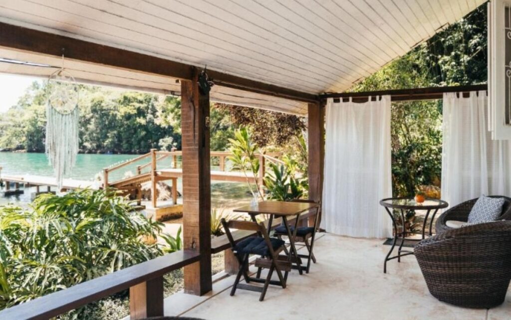 Covered veranda seating area with private boat dock and tropical garden views