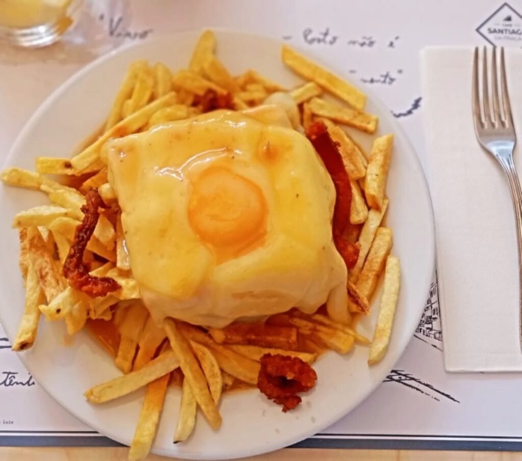 Francesinha with chips and red sauce on branded plate