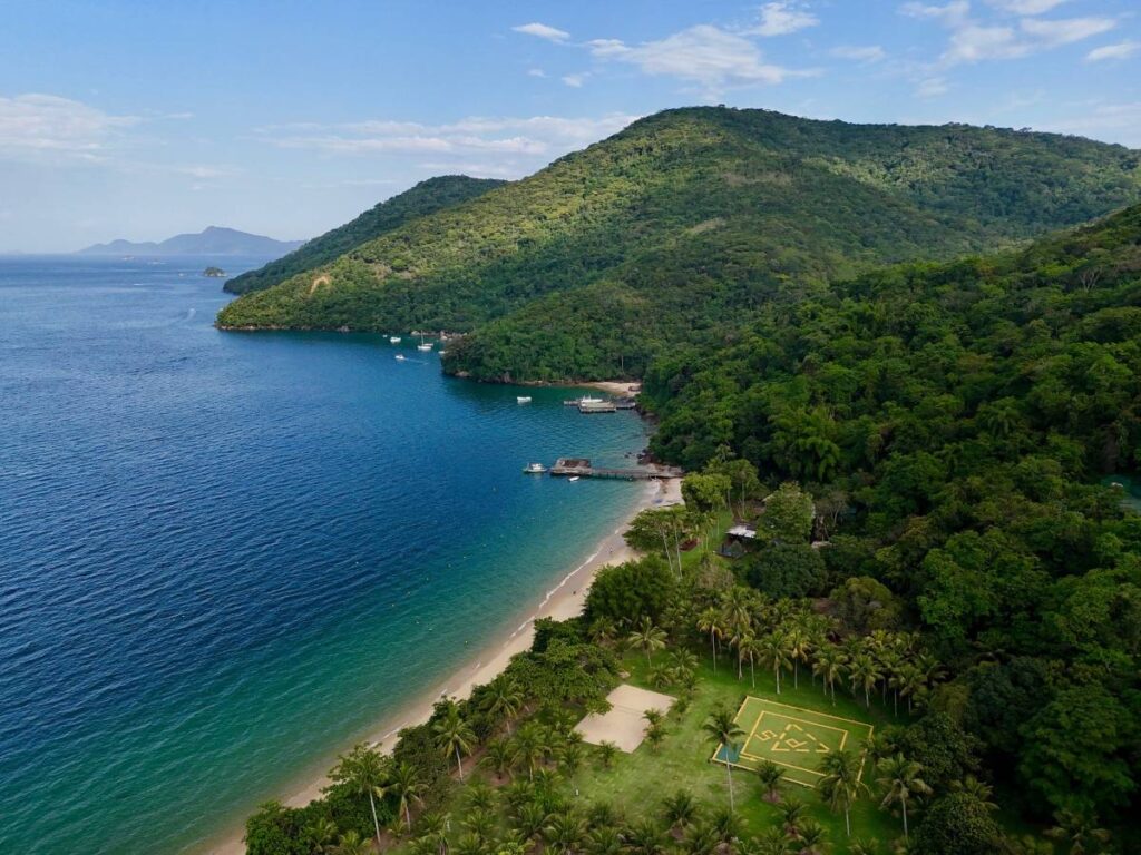 Coastline on Ilha Grande with calm blue water, forested hills, and a narrow sandy beach viewed from above