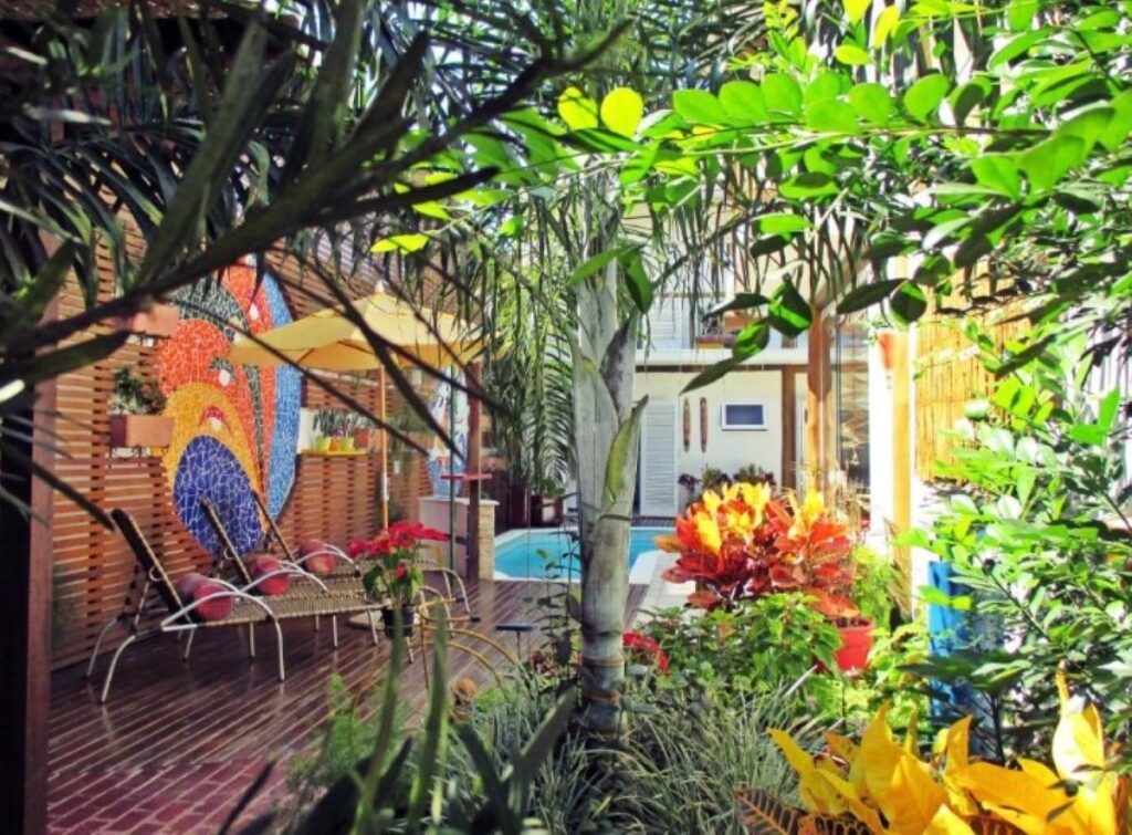 Lush garden courtyard with colourful mosaic wall art, deck chairs and small pool
