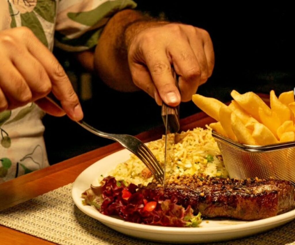 Grilled steak served with garlic rice, salad and golden chips in wire basket