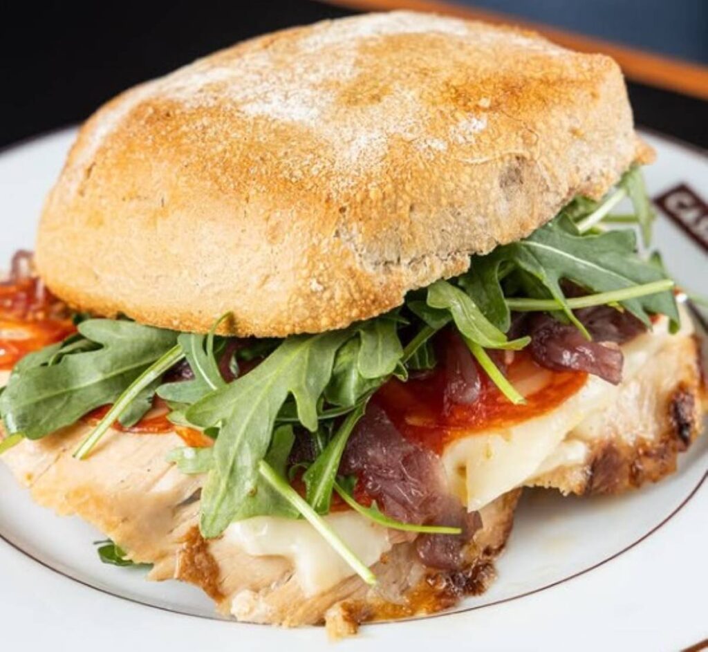 Crusty bread roll filled with melted cheese, cured meat and rocket leaves