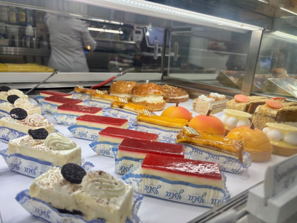 Glass counter in a Granada bakery filled with colourful cakes, slices and individual desserts.