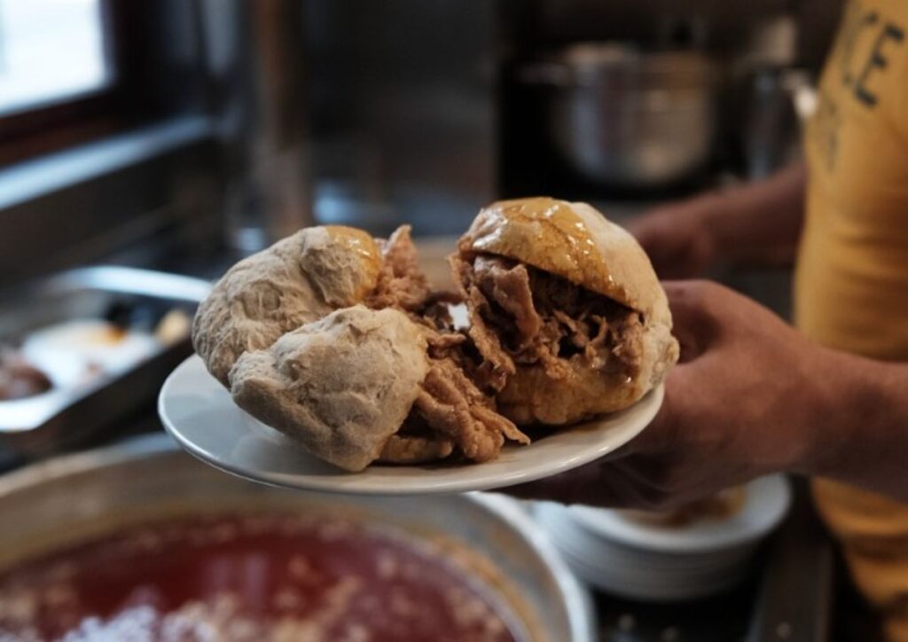 Crusty bread rolls filled with shredded meat on small white plate