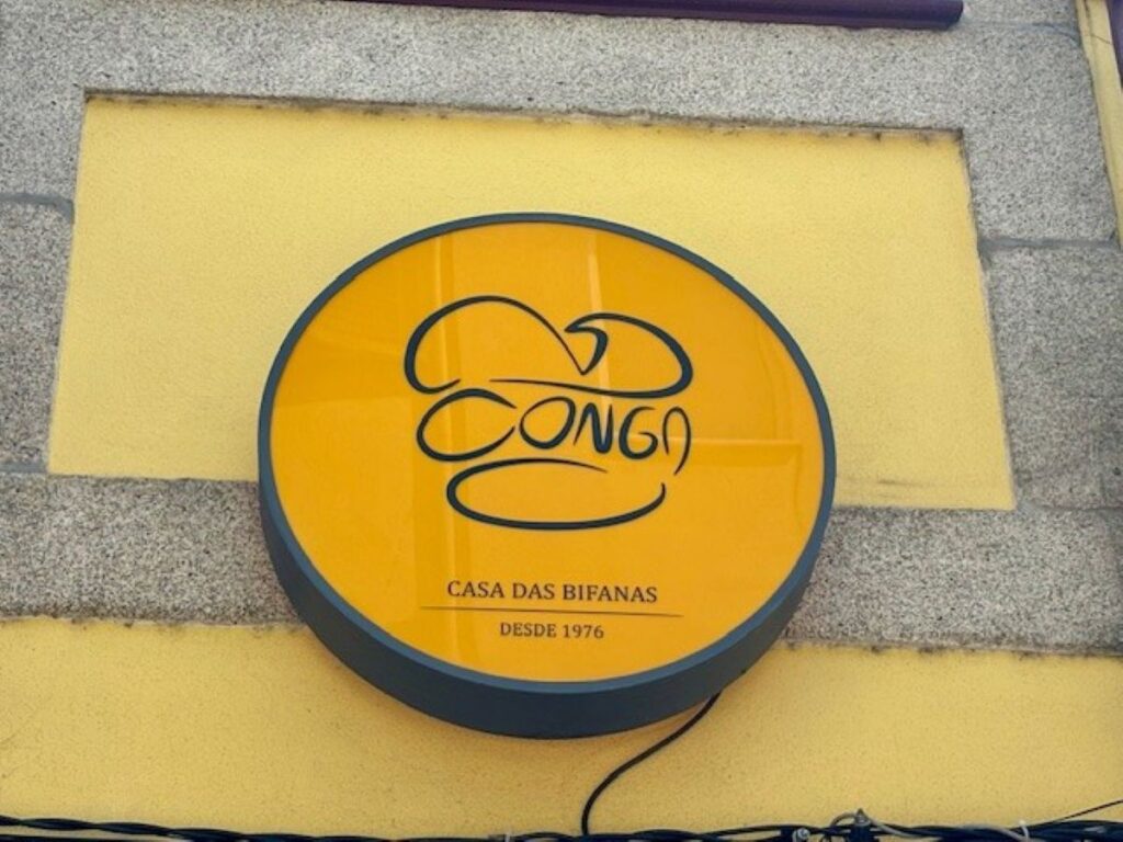 Yellow circular restaurant sign for Conga Casa das Bifanas established 1976