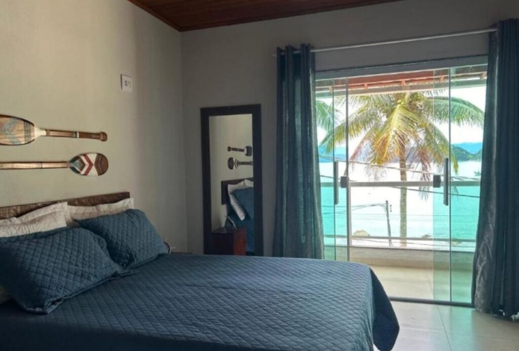 Guest bedroom with ocean view balcony, nautical decor and turquoise bedding