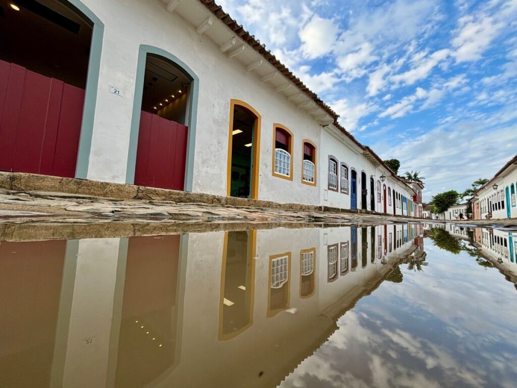 Colourful colonial architecture reflected in rainwater puddle on cobblestone street