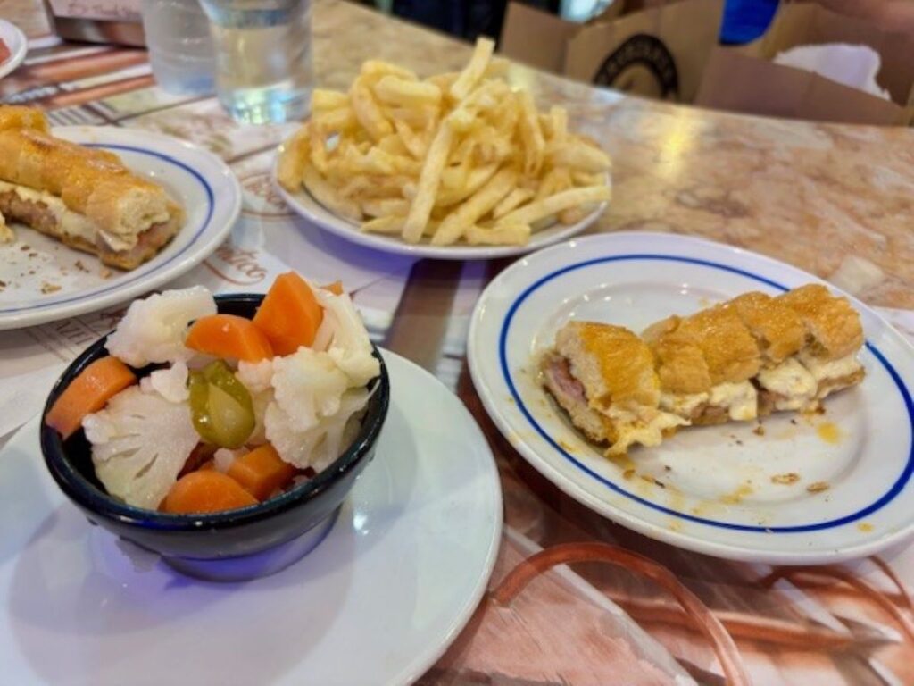 Table spread with Cachorrinho, chips and pickled vegetables on blue-rimmed plates