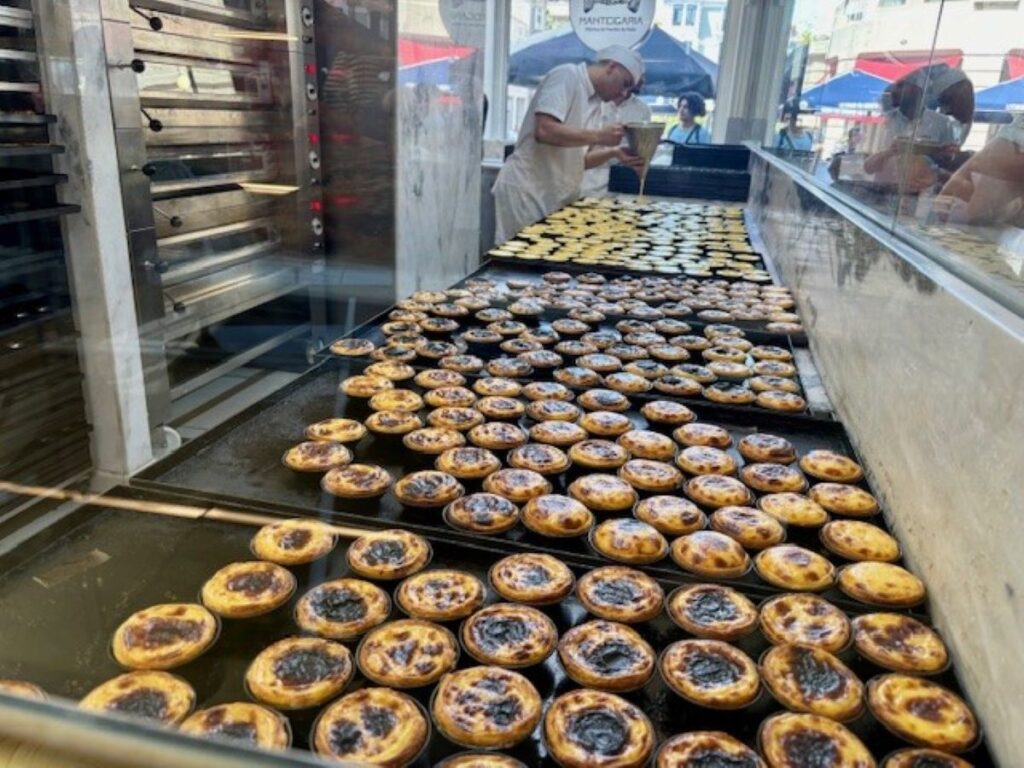 Bakery production line with rows of Portuguese custard tarts cooling on trays