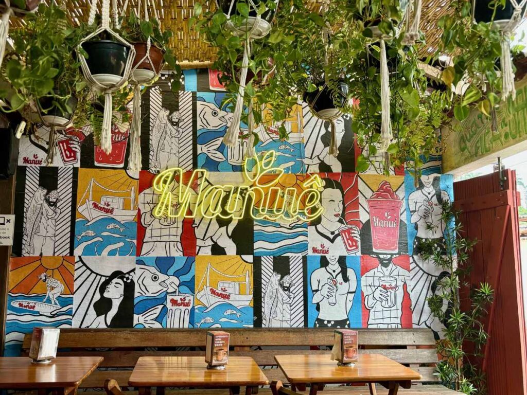 Colourful pop art mural with neon signage and hanging plants at outdoor café