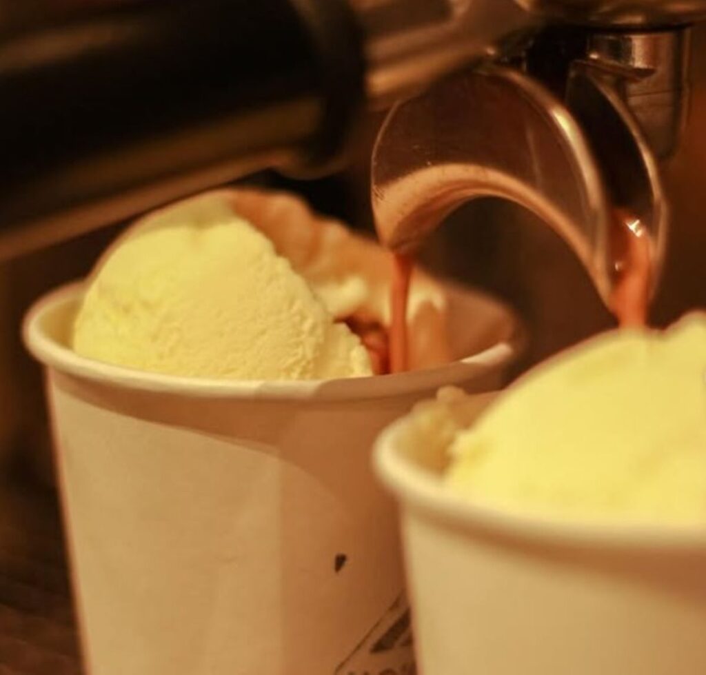 Hot coffee being poured over vanilla ice cream in paper cup